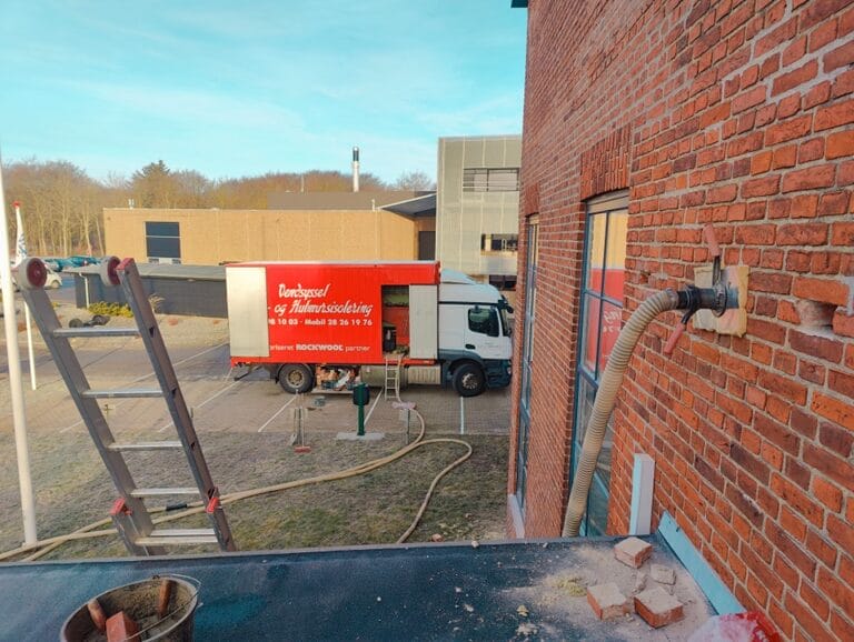 Isoleringsarbejde på murstensbygning med lastbil og slange